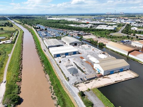 Aerial view of the industrial port area along the river Ouse with warehouses, storage yards, and docked boats in Goole, England, United Kingdom.