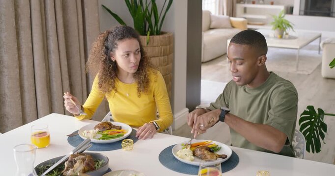 Diverse couple starting dinner at table, cutting and tasting roasted meat with fork and knife