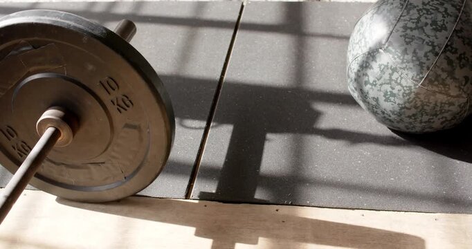 Camera is panning right up, revealing 10kg plate, medicine ball on mat near window showing training