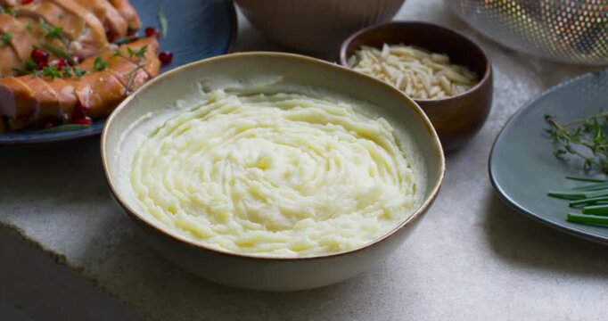 Camera is slowly panning outward after clip start, revealing whipped potatoes and herbs for serving