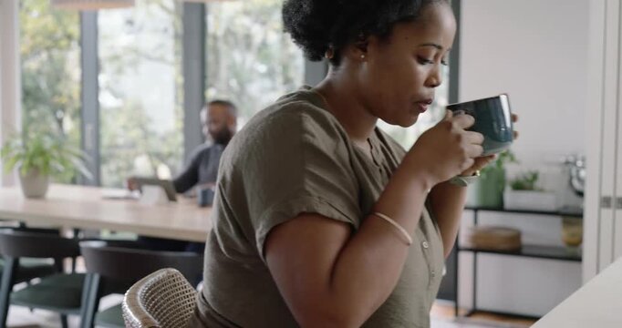 African American couple home, woman scrolling phone after ping, sipping mug, man on tablet, calling