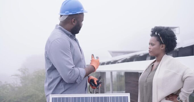 Checking MC4 connectors, African man tech on roof by solar panel, pointing, showing fit to woman