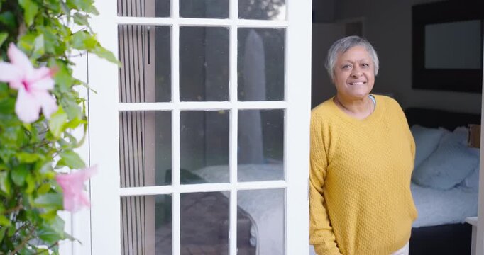 African American woman stepping responding to camera pan smiling near French door vine, copy space