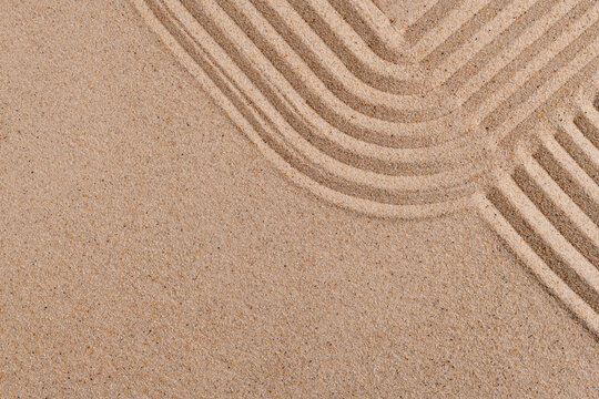 Abstract raked sand texture with curved parallel lines in warm beige tones