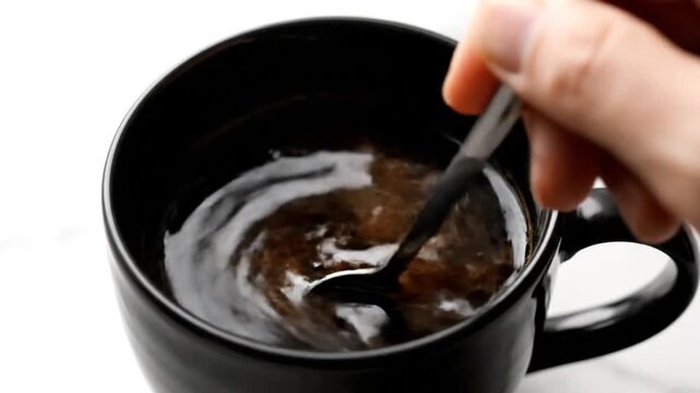 Adding Brown Sugar with Silver Spoon into Black Coffee Mug Macro Shot Top View Adding Sweetener to Hot Beverage on