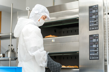 Naklejka premium パン工場,食品工場で働く防塵服,クリーンスーツを着た製造スタッフの男性