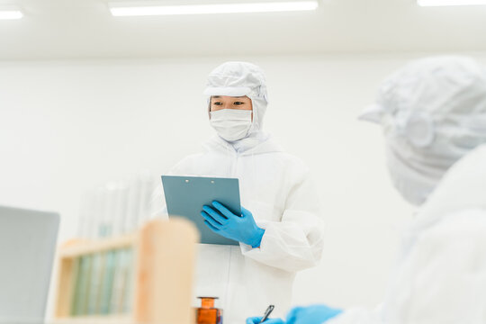薬品工場,製薬会社で薬品開発をするクリーンスーツを着たスタッフ