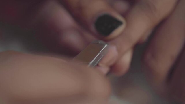 Close up view of professional manicurist using metal nippers to trim cuticles on female finger.