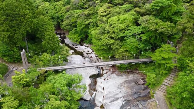 The suspension bridge and unique granite riverbed with potholes at Ayumodoshi Natural Park on Tsushima Island, Nagasaki Prefecture, Japan.