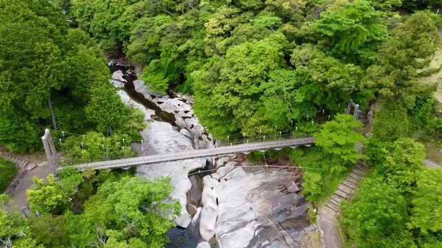 The suspension bridge and unique granite riverbed with potholes at Ayumodoshi Natural Park on Tsushima Island, Nagasaki Prefecture, Japan.