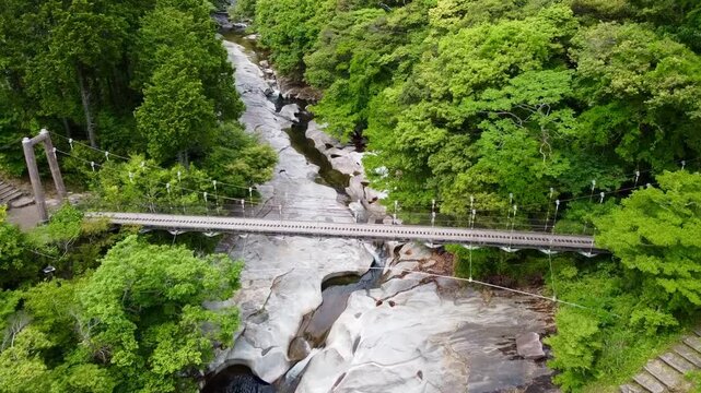 The suspension bridge and unique granite riverbed with potholes at Ayumodoshi Natural Park on Tsushima Island, Nagasaki Prefecture, Japan.