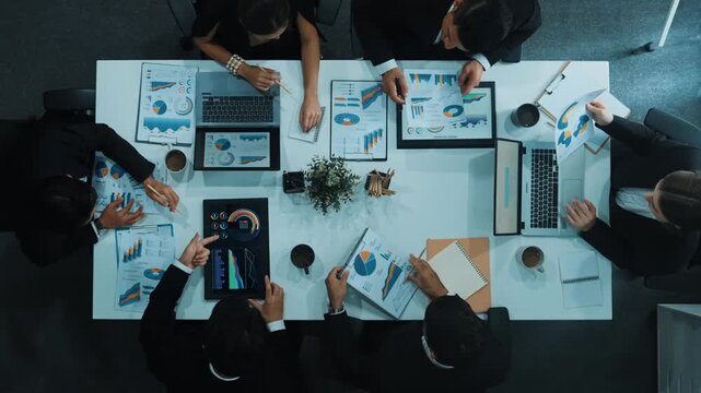 Top down aerial view of business people discussing about financial strategy on table with document and tablet display investment statistic. Time lapse of smart team brainstorm about plan. Directorate.