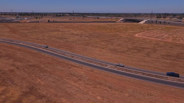 Still Aerial Drone Shot Above Dirt Field With Overpass Train Freeway and Power Lines