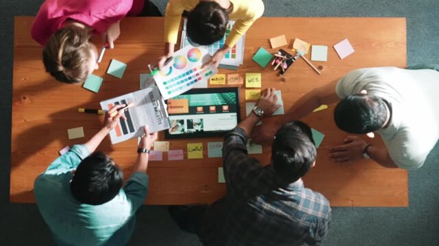 Top view of business people working together to design web design. Aerial view of designer brainstorming and discussing about website interface and looking at tablet with digital design. Symposium.
