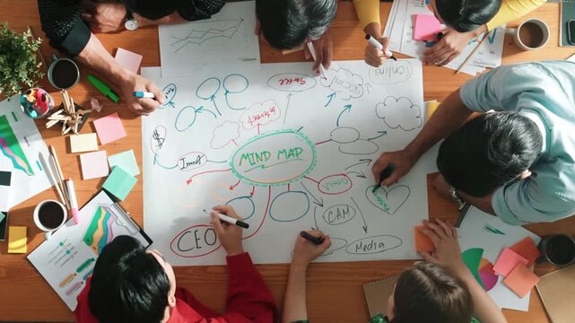 Group of business people writing and making mind map to brainstorming marketing idea at meeting. Top aerial view of investors sharing plan or strategy by using sticky notes and marker. Convocation.