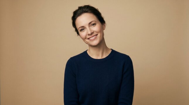Portrait of a smiling woman with dark hair pulled back wearing a navy blue sweater against a neutral background