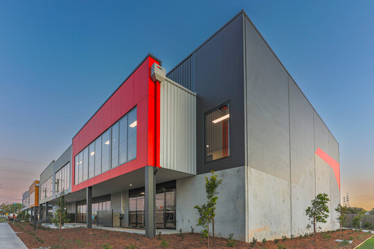 Contemporary industrial warehouse and office building with bold red facade, modern glazing and clean architectural lines. Ideal for commercial property themes.