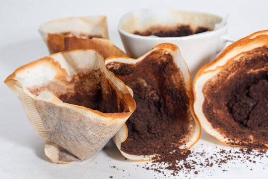 Drip black coffee with coffee filter and coffee grounds on a white background.