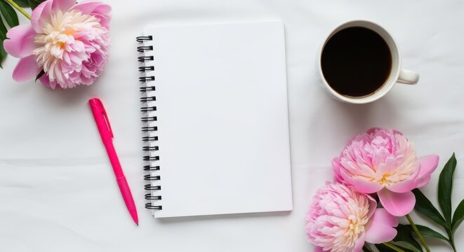 Flat lay of open spiral notebook, pink pen, coffee cup, and pink peony flowers on a white background