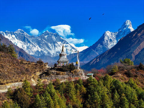 Aerial view of a Buddhist stupa adorned with prayer flags, set against the backdrop of the snow-capped Himalayan peaks in Khumjung, Koshi Province, Nepal.