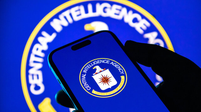 Closeup of a hand holding a smartphone displaying the central intelligence agency cia logo against a blue background