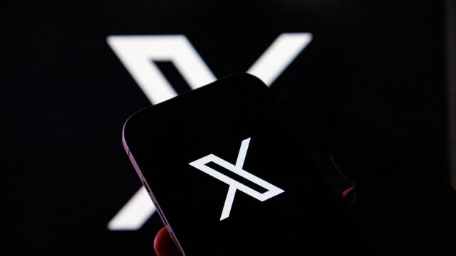Closeup of a smartphone displaying the x logo, formerly known as twitter, with a large x logo in the background
