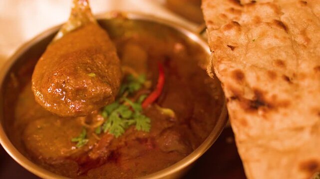 Person Serving Spicy Indian Curry onto Fresh Flatbread in Restaurant