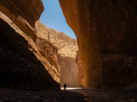 Aerial view of a person standing in a narrow canyon with towering rock walls and a river flowing through the gorge in Nepal.