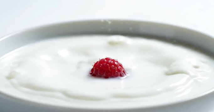 Splash of milk with a raspberry in a white bowl, capturing a dynamic moment of freshness