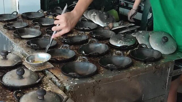 Close-up of preparing traditional Indonesian Surabi, a Javanese rice flour pancake cooked in small cast-iron pans