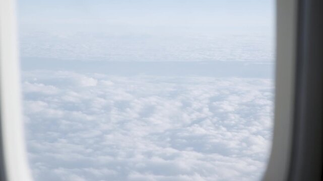 Airplane window view over vast sea of white clouds at high altitude