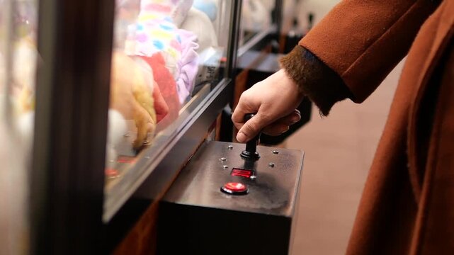 Player uses claw machine to win stuffed toys at arcade