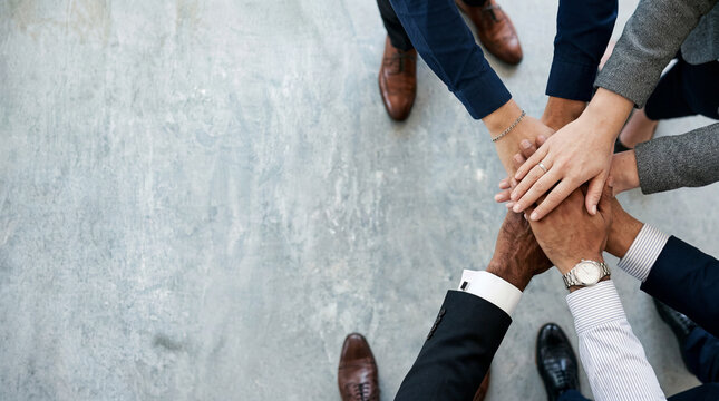 High angle view of corporate colleagues putting hands together symbolizing teamwork and unity