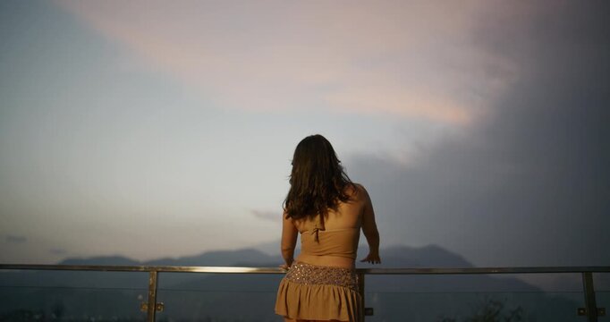 Woman with Windswept Hair in Sequin Outfit on Rooftop Terrace at Twilight	