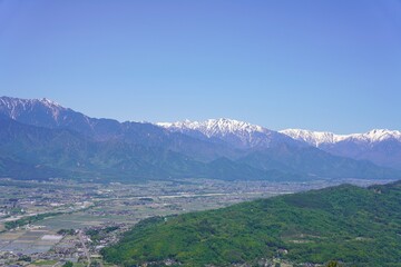 Fototapeta premium 信州 安曇野 長峰山から望む残雪の北アルプスと新緑の安曇野 蓮華岳 針ノ木岳