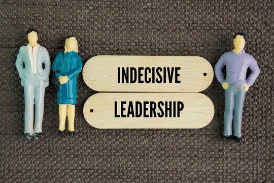 Miniature and wooden people with the words Indecisive Leadership. management style characterized by the chronic inability to make clear, timely choices.