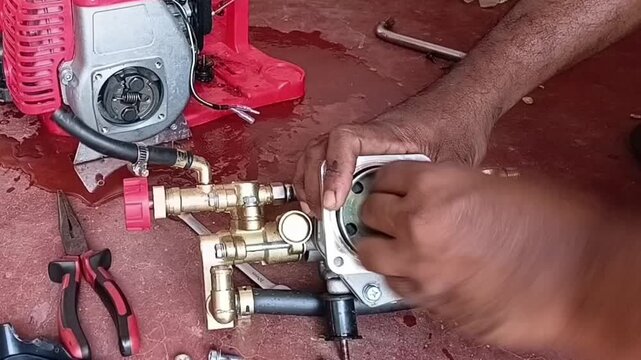 Close Up Of Mechanic Cleaning Debris From Two Stroke Gasoline Engine Clutch Bell Drum Using Sandpaper For Agricultural Power Sprayer Maintenance
