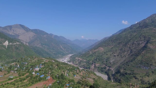 Cinematic wide angle aerial view of a deep mountain river valley and rugged mountain ranges