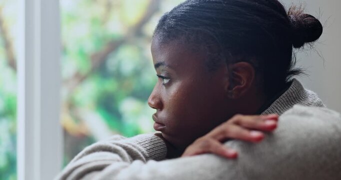 Black woman, window and anxiety in home for mistake, overthinking or fear with regret or unhappy. Trauma, stress or female person with depression in living room with worry for mental health crisis
