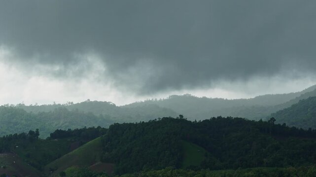Dynamic storm clouds formation timelapse rolling over green hills and mountains before rain.