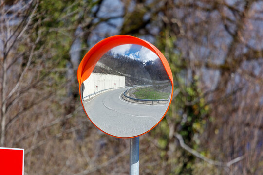 Curved mirror reflects winding road and distant hills
