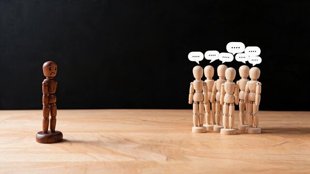 Lonely wooden figure excluded from group, social isolation concept, bullying metaphor, outcast feeling, loneliness emotion, mental health awareness, discrimination issue