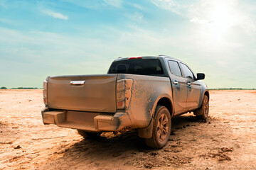 Muddy 4x4 pickup truck parked on a dry dirt field back view after an off-road adventure. © Emma Grace