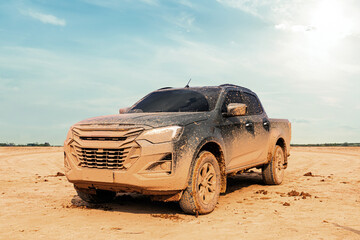 Muddy 4x4 pickup truck parked on a dry dirt field after an off-road adventure. © Emma Grace