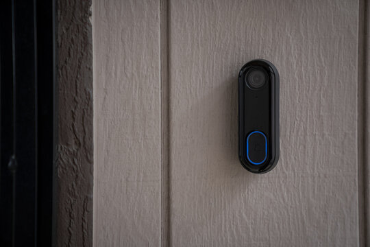 Black smart doorbell near modern residential entrance door showing security system and access control technology for modern home protection