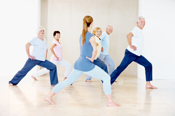 Fototapeta premium Pilates, instructor and stretching with elderly people for wellness, support and fitness in retirement. Senior group, trainer and lunge at facility for teaching, muscle warmup and exercise class