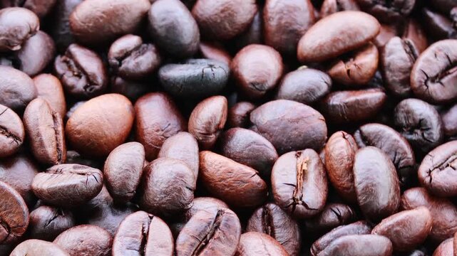 video of roasted coffee beans moving slowly past camera showcases their rich texture, and premium quality, making them perfect for beverages and coffee shops.
