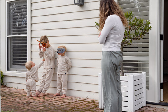 Toddler boy reaching for his older brother's mask with family looking on