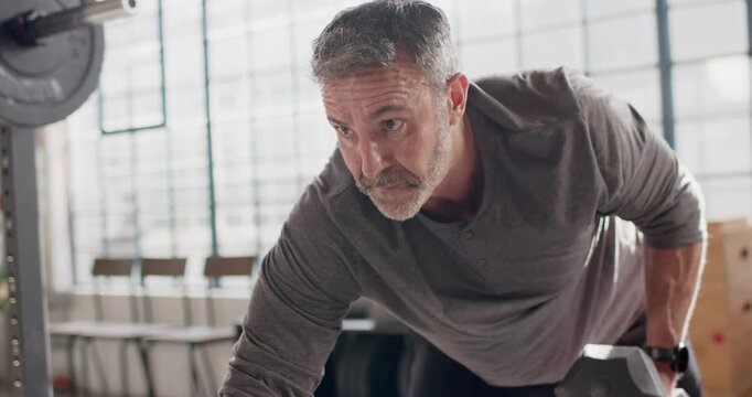 Bracing on bench, man gripping hex dumbbell, rowing to ribs, pausing, lowering for strength at gym