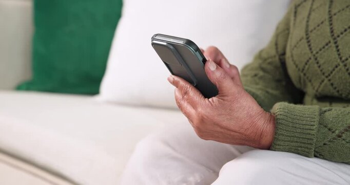 Senior African American woman sitting sofa green sweater holding phone tapping checking, copy space